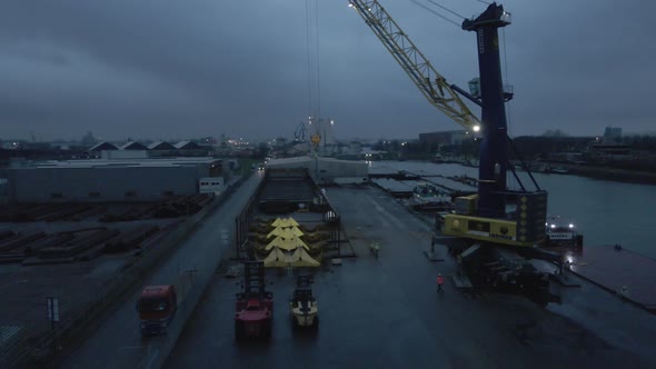 Ship Unloader And Forklifts At Terminal With People Working At Night. - high angle