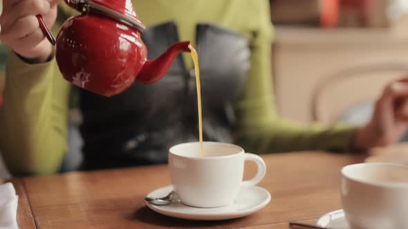 Woman Pouring Tea in a Cafe