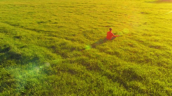 Low Altitude Radial Flight Over Sport Yoga Man at Perfect Green Grass. Sunset in Mountain.