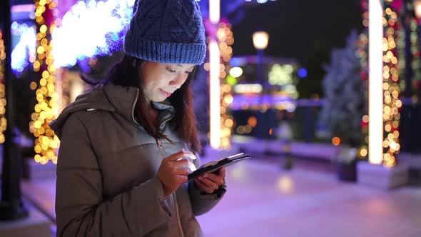 Woman using mobile phone in Yokohama city at night