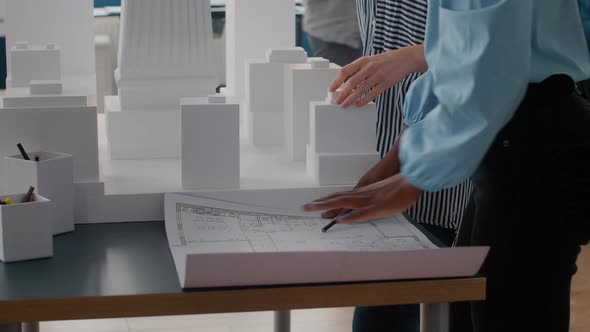 Close Up of Architects Placing Blueprints Plan on Table to Work on Urban Project with Building Model