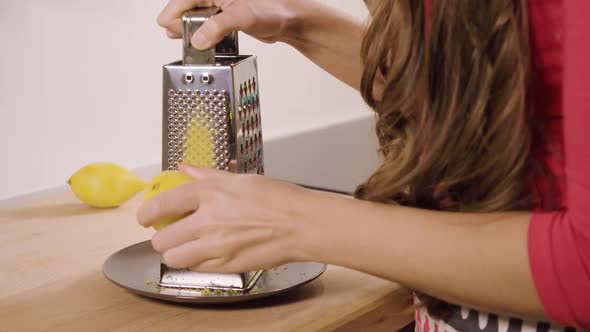 A Woman Grates a Lemon in a Kitchen - Closeup