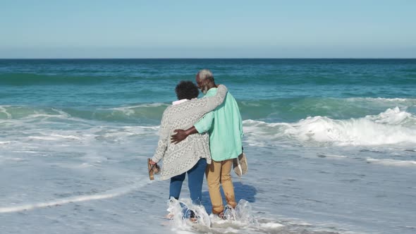 Senior couple walking in the water at the beach