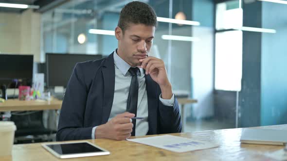 Young African Businessman Thinking and Reading Documents