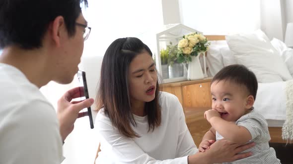 Infant Asian Boy with Mother Watching Video on Smartphone and Laughing