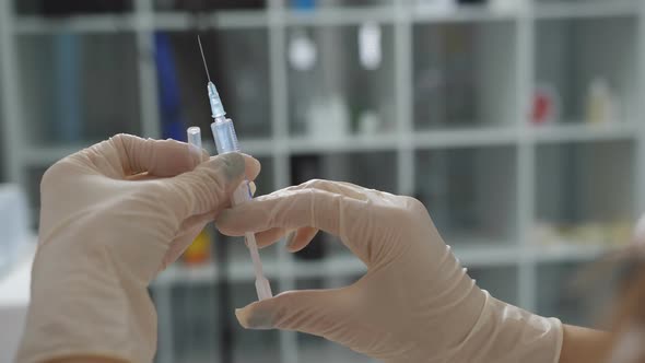Close Up of Female Doctor Holding and Squeezing Syringe with Medicine alt