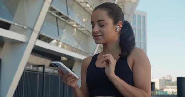 Fit Woman Runner Using Smartphone and Listening Music with Earphones After Sport Fitness Training