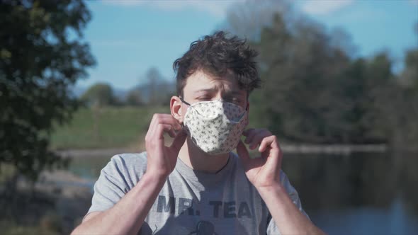 Young man puts on homemade white corona virus cotton mask MEDIUM SHOT