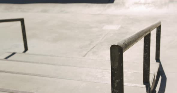 Low section of caucasian man riding and jumping on skateboard on sunny day