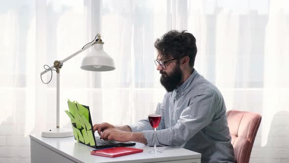 Man Types and Then Drink a Glass of Wine and Looks Happily at the Screen