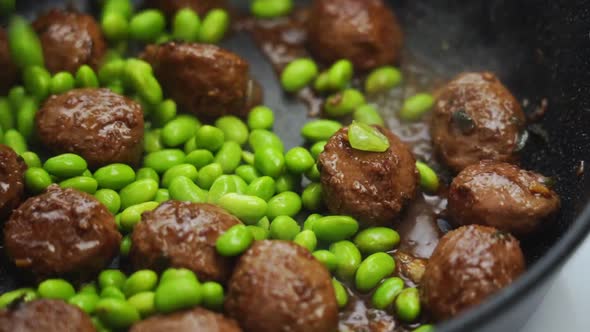 Unrecognizable person cooking green beans and meatballs