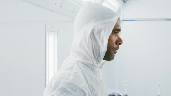 Mixed race male car mechanic putting protective clothes on and looking at camera