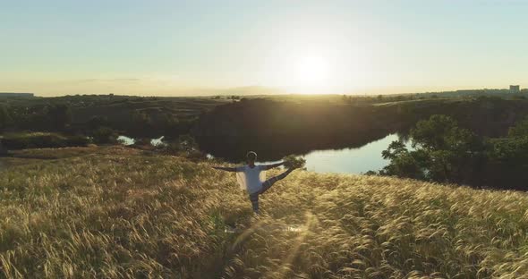 Girl meditates on a beautiful meadow at sunset