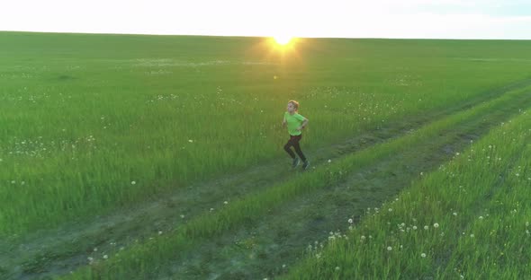 Sporty Child Runs Through a Green Wheat Field. Evening Sport Training Exercises at Rural Meadow. A