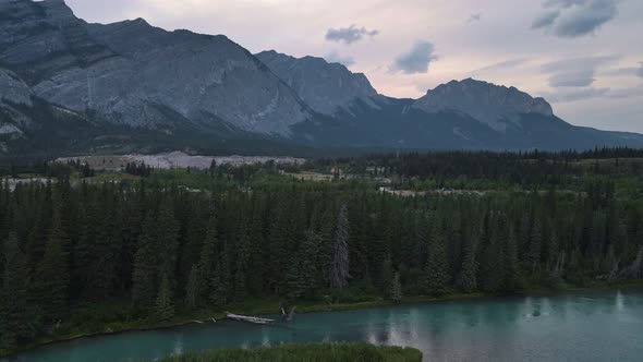 Kananaskis River flowing through dense lush forest below the stunning Rocky Mountains at blue hour i