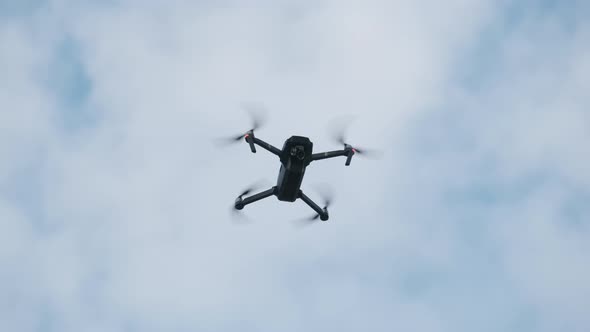 Drone Hangs in the Air Against the Blue Sky, View From Below. Slow Motion