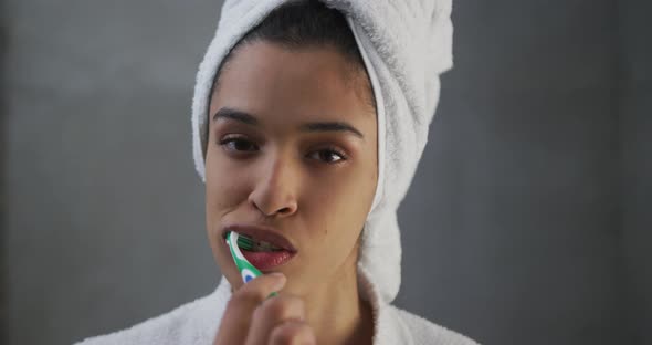 Portrait of mixed race woman brushing her teeth in bathroom