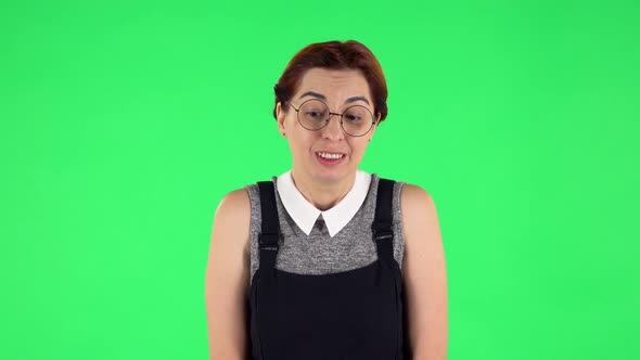 Portrait of Funny Girl in Round Glasses Is Smiling and Expressing She Innocent. Green Screen