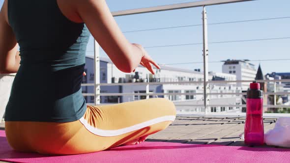 Mixed race gender fluid person practicing yoga meditation on roof terrace