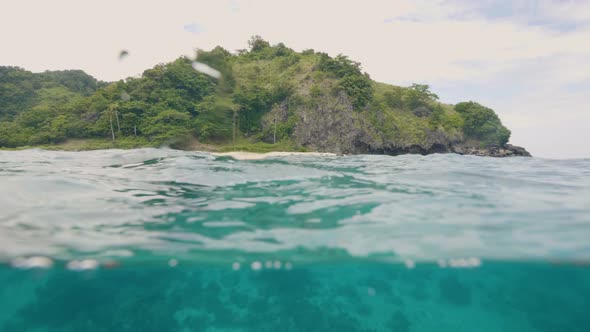 Tropical Island and Blue Sea Water Waterline View. Green Sea Island and Splashing Turquoise Water