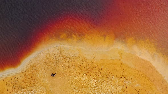 Man is standing on the clay quarry and looking on the red water