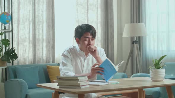 Asian Man Student Being Sleepy While Reading A Book At Home