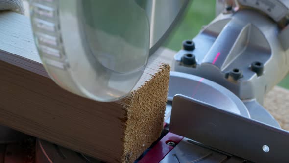 DIY Project Woodworker in Gloves Cuts Off 4X4 Wooden Post on Mitre Saw Close-up