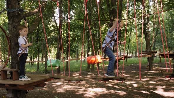 Two Little Boy Moves Confidently Along Ropeway in Recreation Park