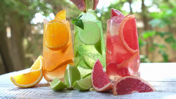 Squeezes Fresh Lime Juice Into An Ice Drink Mojito. Mix Of Three Ice Refreshing Drinks With Orange