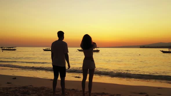 Romantic couple engaged on exotic resort beach wildlife by blue green ocean and white sand backgroun