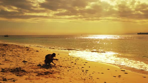 Single male fishing alone on exotic shore beach lifestyle by turquoise sea and bright sandy backgrou