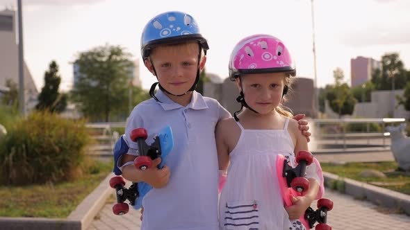 Portrait of Children in Helmets with Skateboards in Their Hands in the Park.