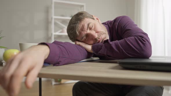 Exhausted Middle Aged Caucasian Man Sleeping on Table at Home