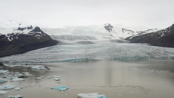 Iceland glacier wide shot with water and blue ice with drone video moving down.