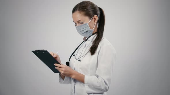 Female doctor makes notes on a patient's medical record.