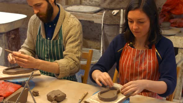 Male and female potters molding a clay