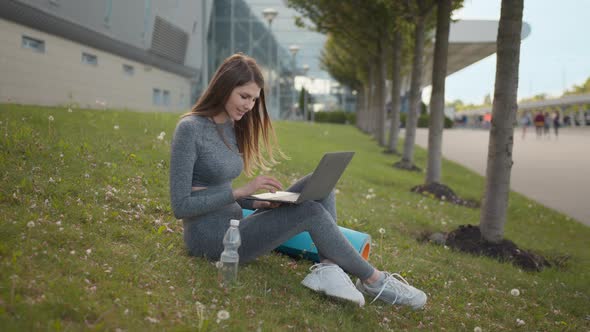 Portrait of Fitness Woman Using Laptop Sitting on Mat Outdoors