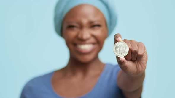 African American Lady Showing Silver Bitcoin Standing On Blue Background