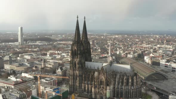 AERIAL: Circling Around Beautiful Cologne Cathedral with Central Train Station in Beautiful Hazy