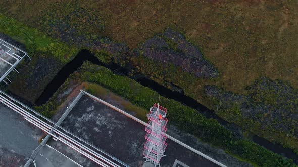 A Drone Descends Over a Metal Lighting Tower at a Power Generating Station