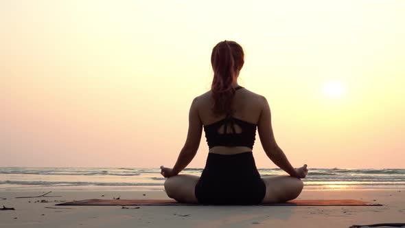 Slow motion of woman practice yoga lotus pose to meditation with summer vacation on the beach