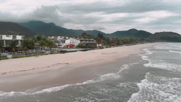 Drone footage of the beach above the sea, mountain in front of the sea, cloudy day, waves, landscape