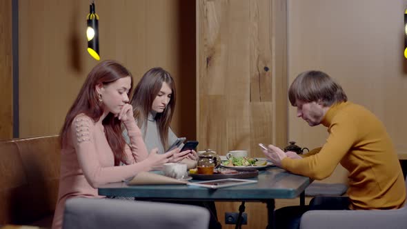 Three Device Addicted Absorbed Millennials Surfing Internet and Using Social Media on Smartphones