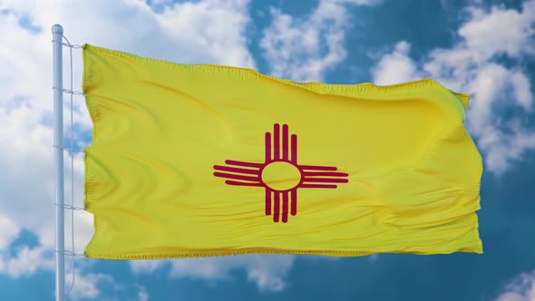 New Mexico Flag on a Flagpole Waving in the Wind Blue Sky Background