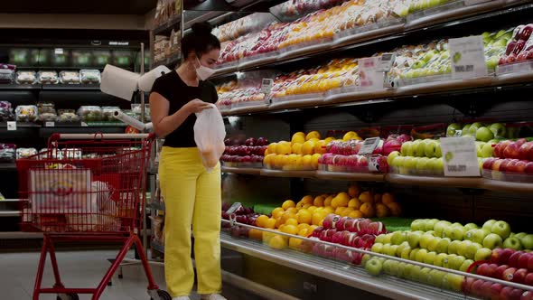 A Young Woman in a Mask From the Coronavirus Epidemic Stands in the Grocery Department of a