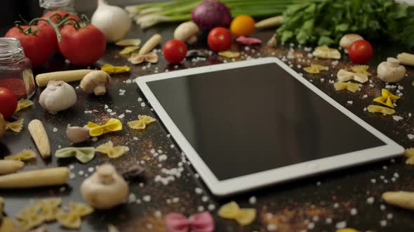 Digital Pad Amidst Pasta Ingredients in Kitchen