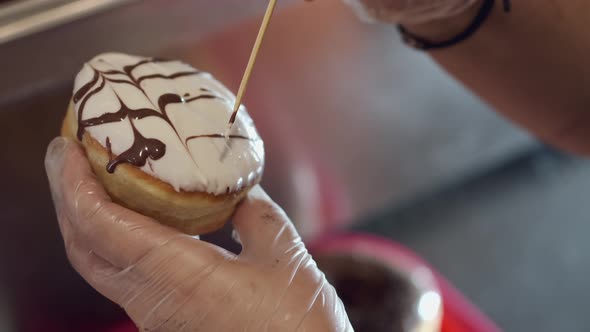 The Baker Is Decorating a Donut with a Topping