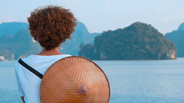 Slow motion: Woman with traditional vietnamese hat looking at unique view of Halong Bay, Vietnam