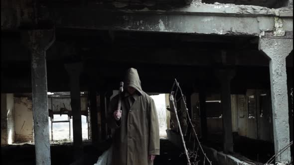 a Man in a Dark Cloak with a Bloody Ax Walks in a Dark Abandoned Room