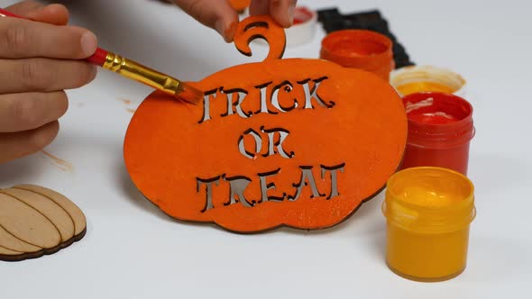 Children make their own Halloween decor. Children paint a pumpkin orange with the inscription
